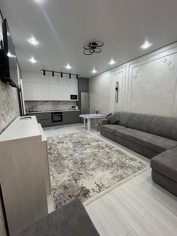 uma sala de estar com um sofá e uma mesa em Beautiful DAY em Almaty
