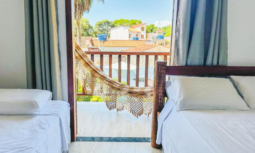 Dos camas en una habitación con vista a un balcón. en POUSADA SOL DE VERÃO - Cumuruxatiba -BA, en Cumuruxatiba