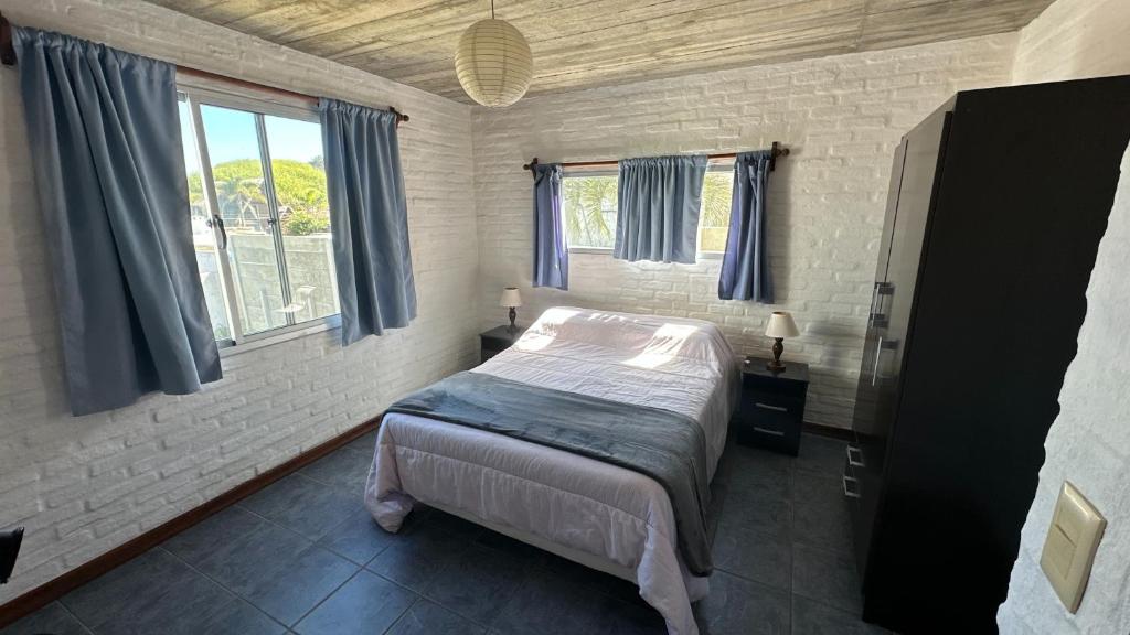 a bedroom with a bed and two windows at Los Horneros Aparts - La Aguada in La Paloma