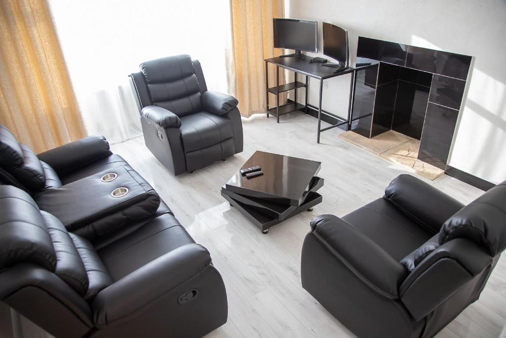 ein Wohnzimmer mit schwarzen Ledermöbeln und einem Kamin in der Unterkunft Villa Emma - Modern Bungalow with EV Point, Free Parking & Workspace in Northampton