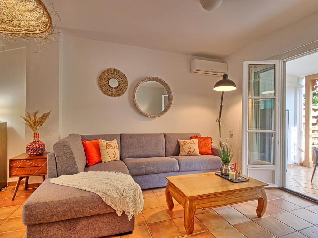 a living room with a couch and a table at Charmante Villa "Coquelicot" à Orient Baie, Proche Plage et Commerces, Confort et Détente Garantis - FR-1-734-10 in Orient Bay