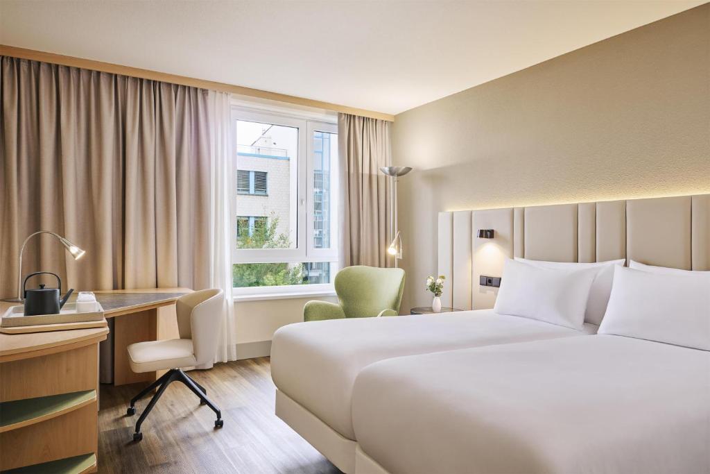 ein Hotelzimmer mit Bett, Schreibtisch und Fenster in der Unterkunft NH Leipzig Messe in Leipzig