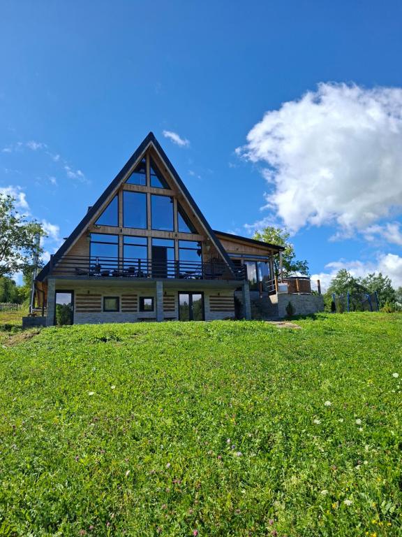 a large house on a hill with a green field at Cabana 3 Stejari Maramureș in Călineşti