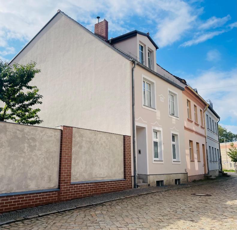 a white building next to a brick wall at Ferienwohnung auf der Spreeinsel in Spremberg
