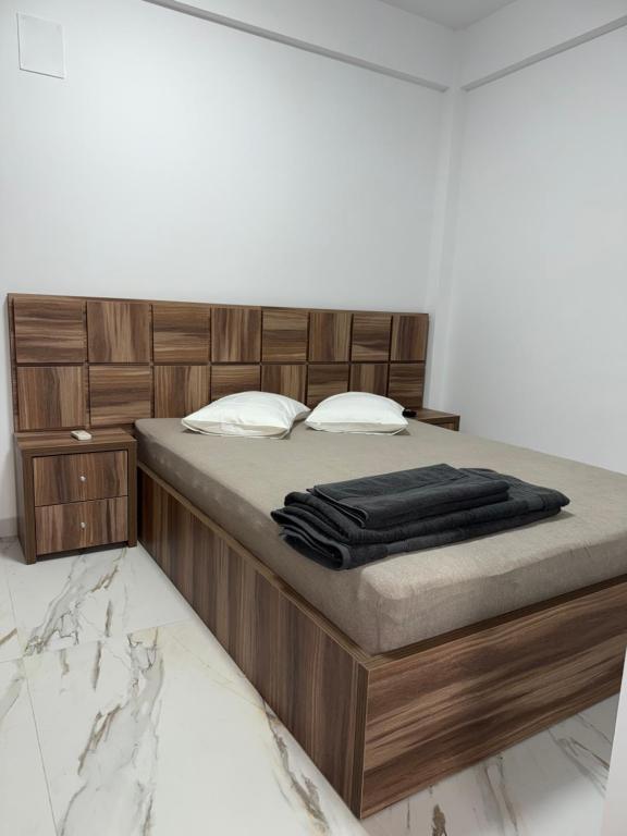Un dormitorio con una cama con cabecero de madera. en Urban Confort Studio, en Popeşti-Leordeni
