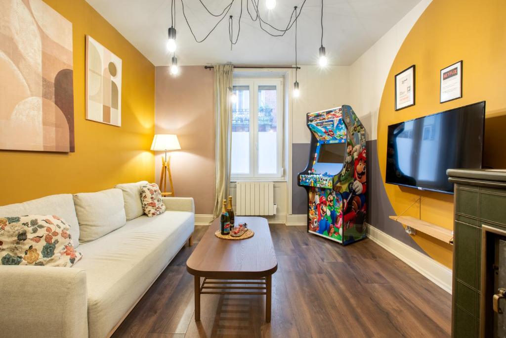 a living room with a couch and a tv at Zenora Loft Hot Tub & Arcade in Downtown in Mulhouse