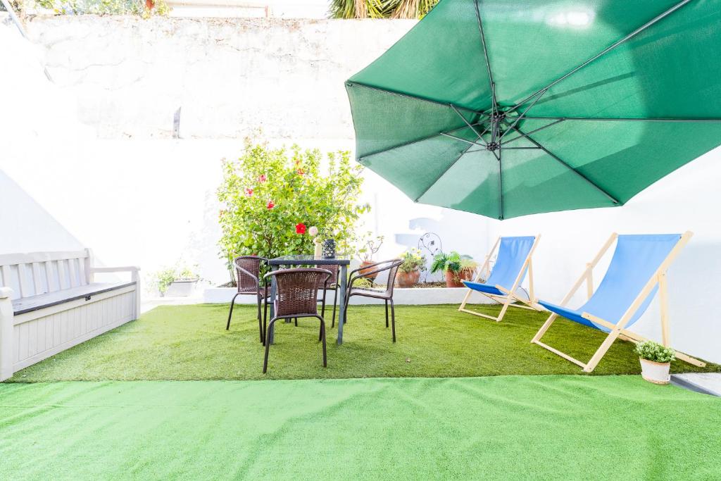 a patio with a table and chairs and an umbrella at Peaceful 2-bedroom House with Garden at the heart of Benfica in Lisbon