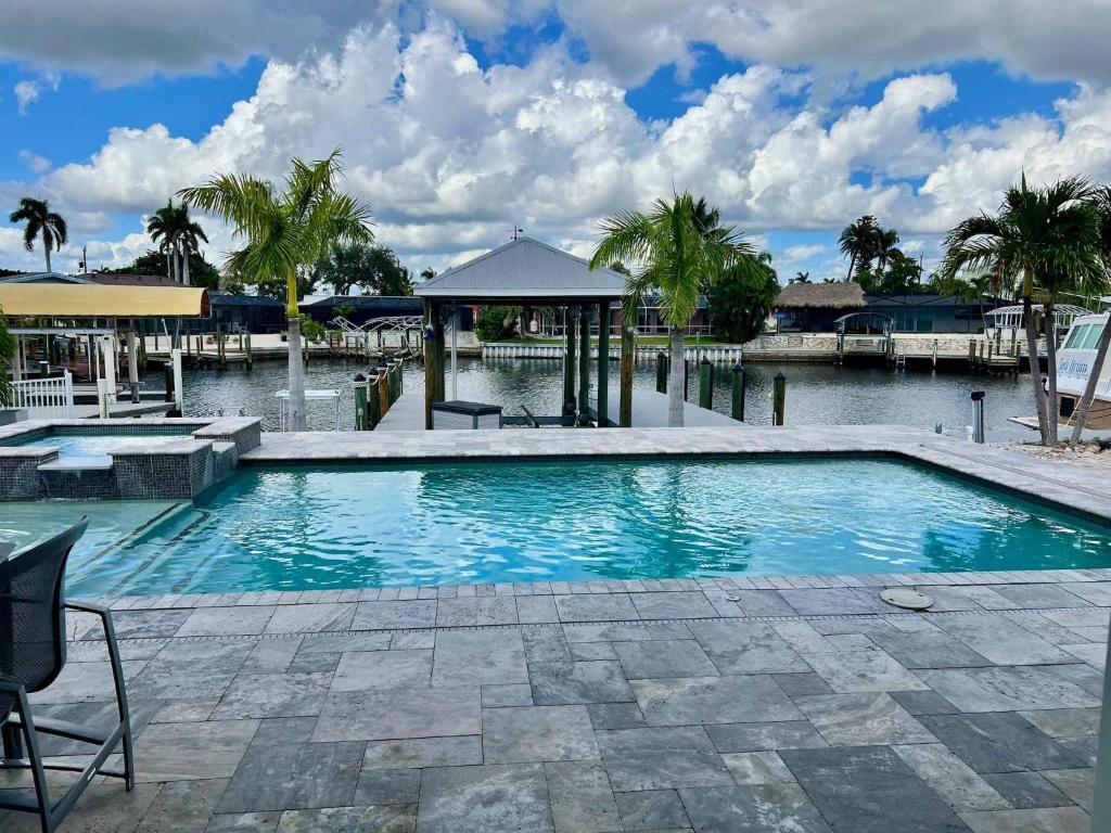 a swimming pool with palm trees and a body of water at Luxury Seabreeze Retreat in Fort Myers Beach
