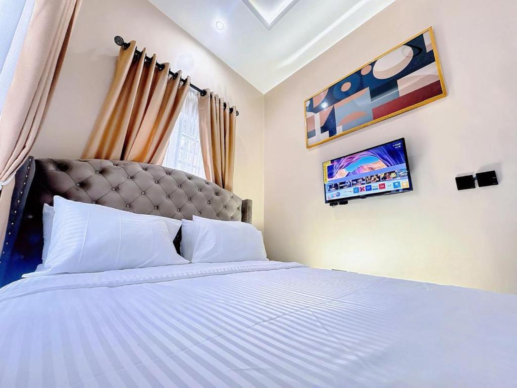 una camera da letto con un letto grande con cuscini bianchi di La Vintage Apartelle - Apartment Paris a Ikeja