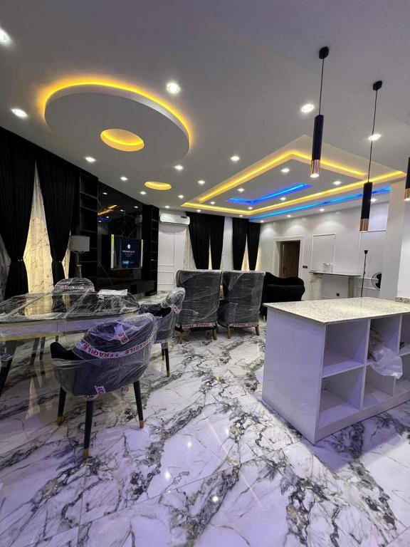 Un vestíbulo con suelo de mármol con sillas y mesas. en Ladi's place Wuye, Abuja, en Abuja