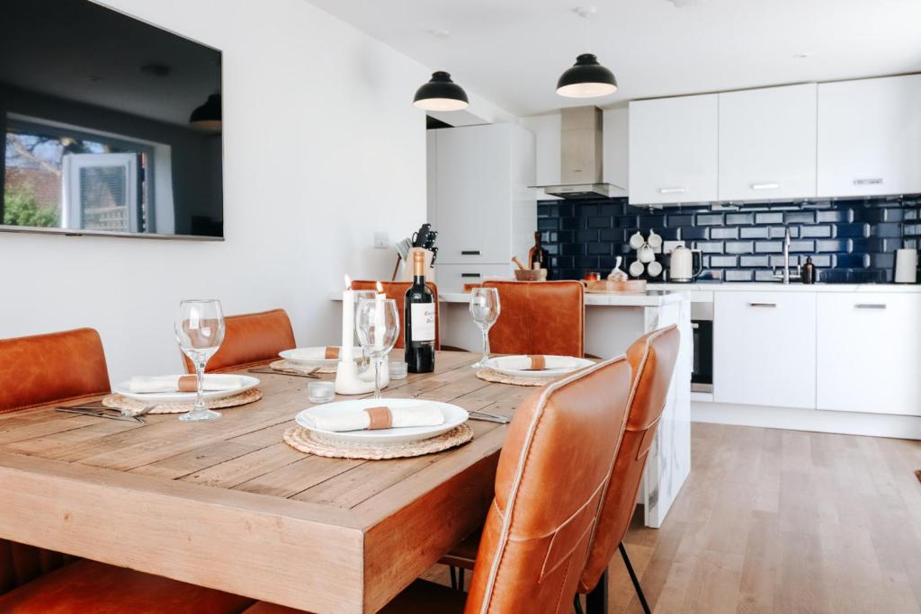a kitchen with a wooden table with chairs and a dining room at The Coachhouse by Solace Stays in Bassaleg