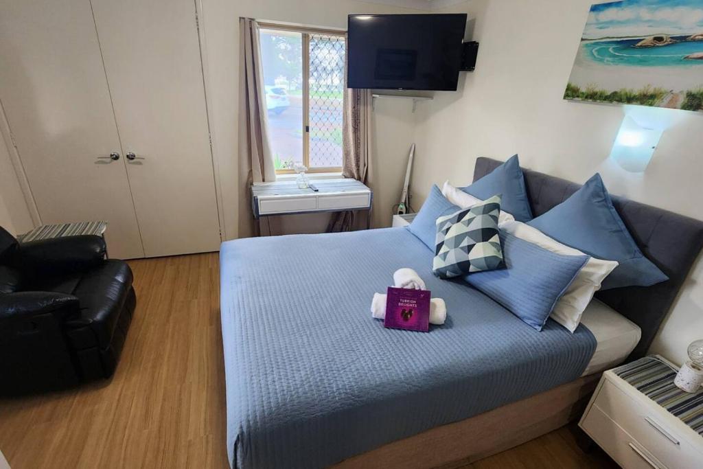 a bedroom with a large bed with blue pillows at Cosy Bayside Studio in Esperance