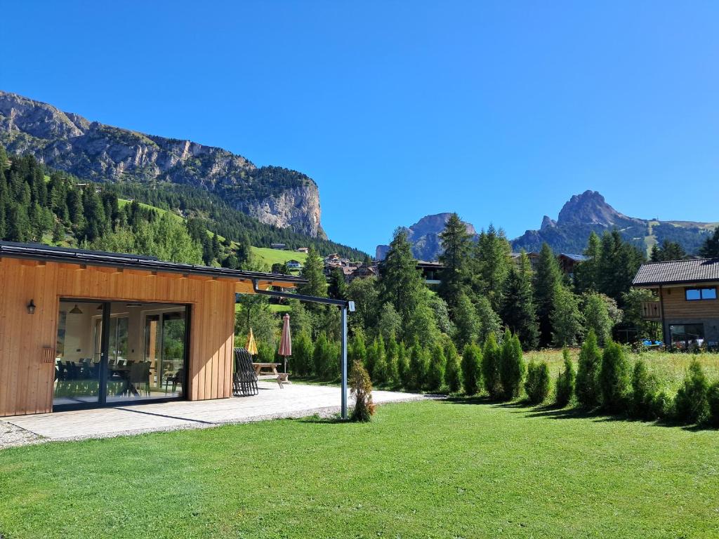 a house in a field with mountains in the background at Dumbria Dolomites in Selva di Val Gardena