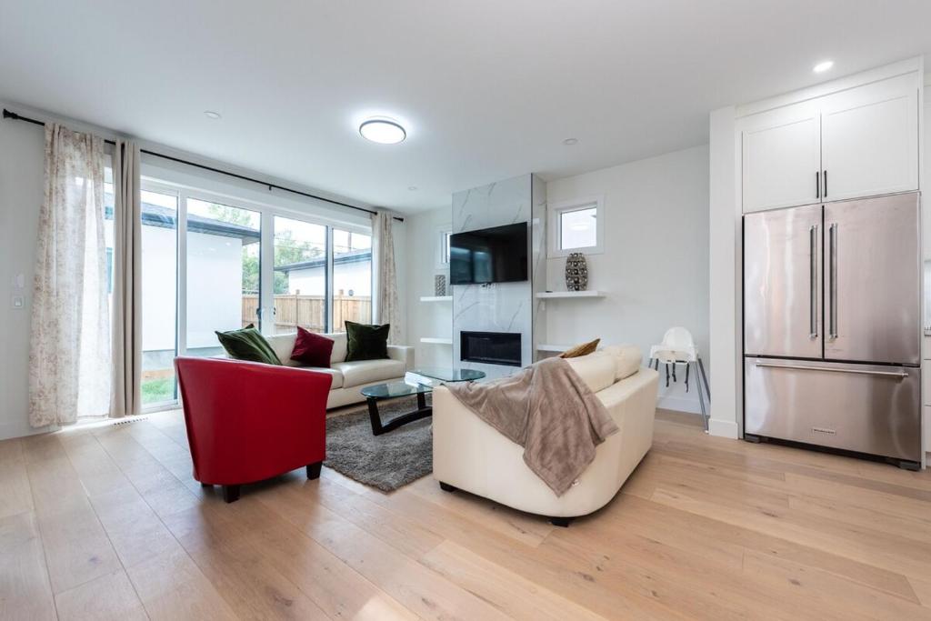 a living room with a couch and a red chair at Luxury Home Near DT, New Build, High-End Features in Calgary