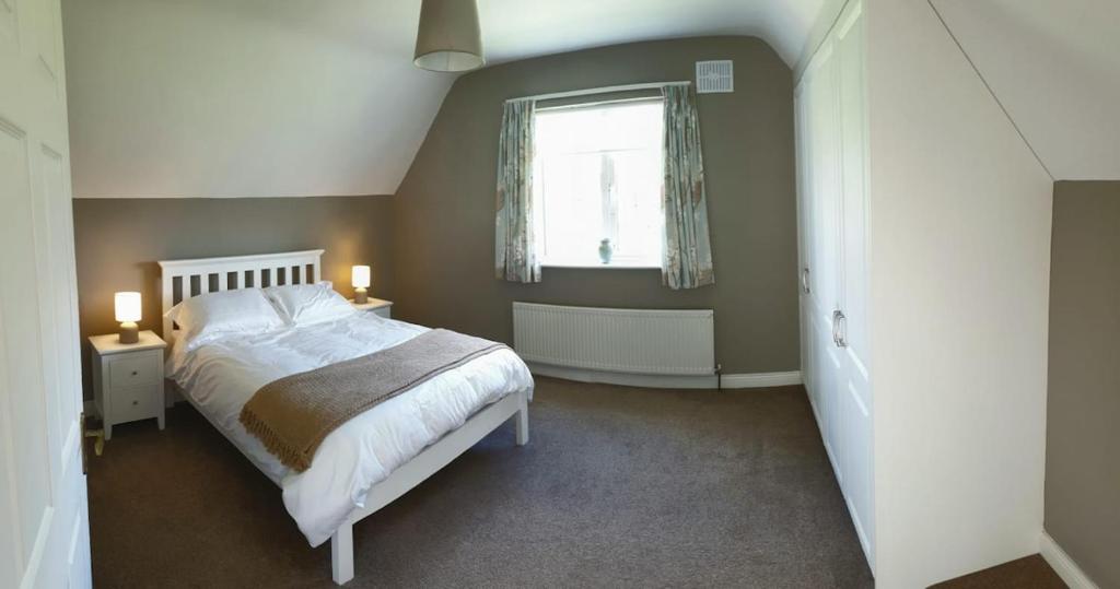 a bedroom with a large bed and a window at Solas na Gealai, entire house, sleeps 8 in Mountshannon
