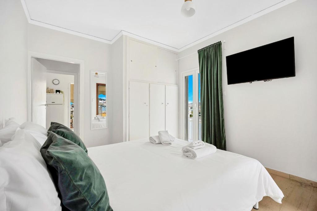 a white bedroom with a white bed and a flat screen tv at Athens sky & Acropolis view rooftop apartment! in Athens