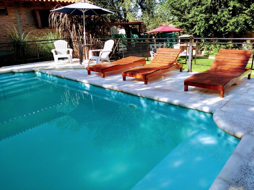 a swimming pool with two chairs and an umbrella at Cabaña en el centro La Casona in Mina Clavero