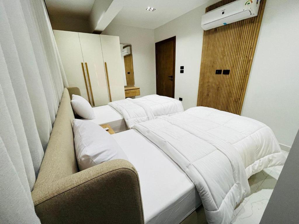 two beds in a room with white sheets at كمبوند الكناريا عماره 81 in Sheikh Zayed