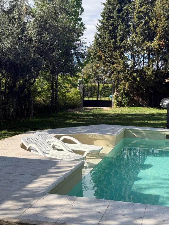 ein Pool mit zwei weißen Stühlen daneben in der Unterkunft Encantadora casa de campo in Ciudad Lujan de Cuyo