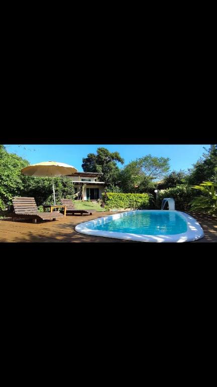 una gran piscina azul con sombrilla en Apartamento Morada Madu, No Centrinho da Praia do Rosa, en Imbituba