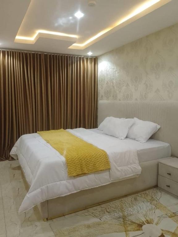 a bedroom with a large bed with a yellow blanket at Aquarian Spring Homes in Ikeja