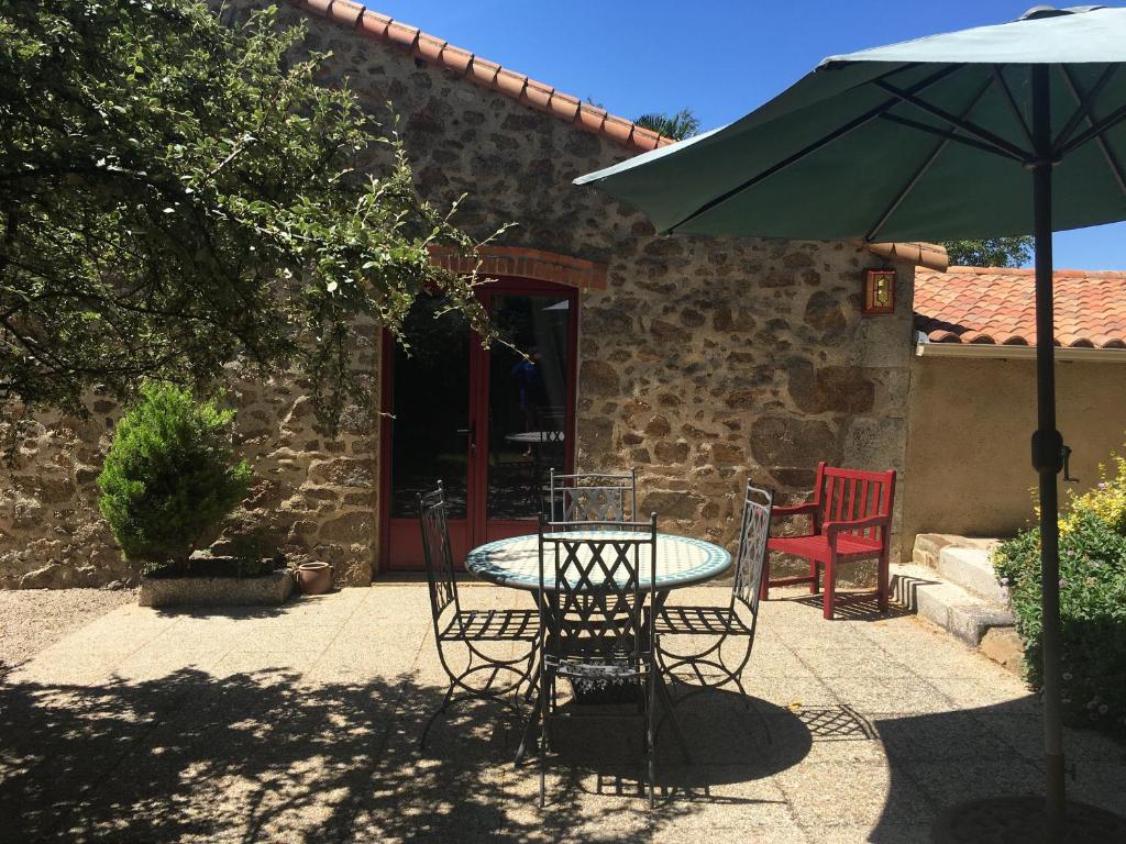 a table and chairs and an umbrella on a patio at Gîte charmant à la campagne avec terrasse, proche du Puy du Fou et de la rivière Sèvre - FR-1-426-249 in Sevremont