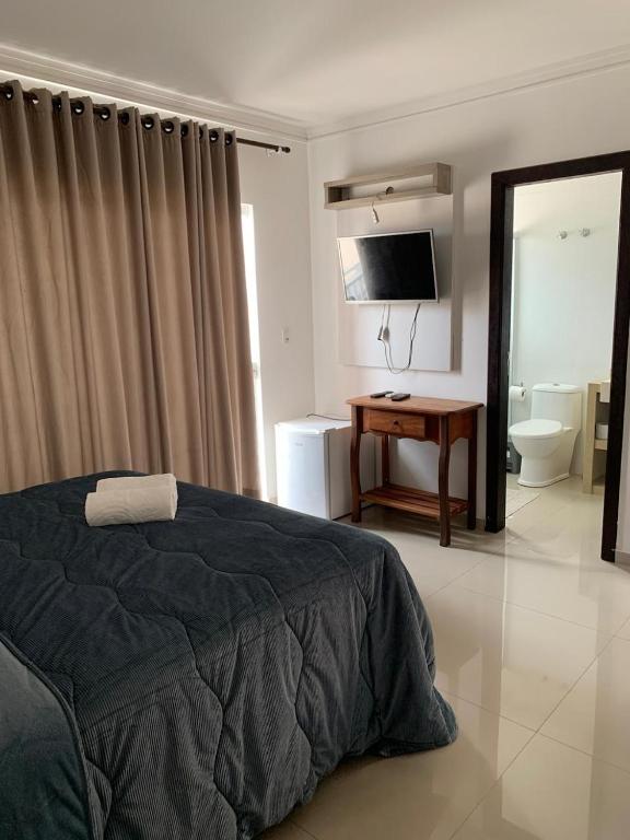 a bedroom with a bed and a desk and a television at Pousada VÔ REY in Penha