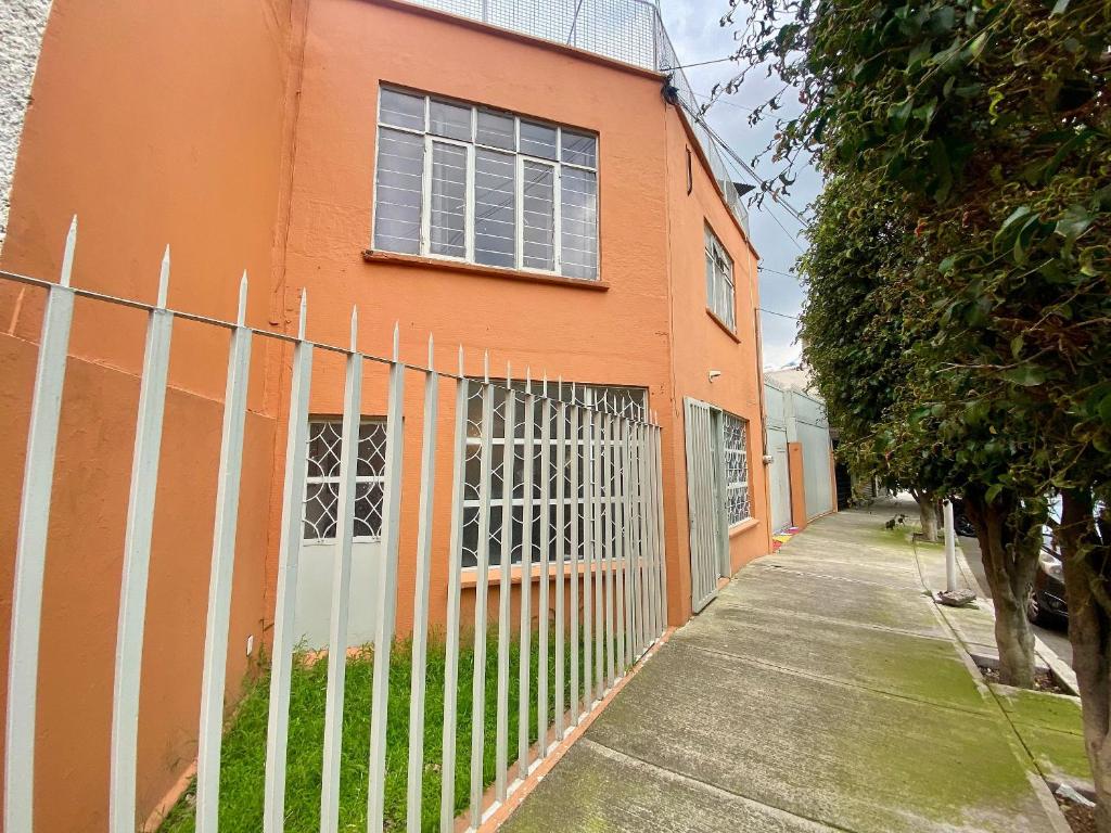 a fence in front of a orange building at Music Guest House in Mexico City