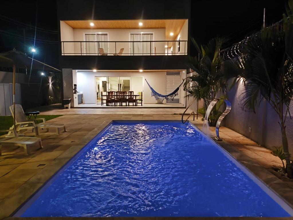 ein großer blauer Pool vor einem Haus in der Nacht in der Unterkunft Casa Barramar Temporada in Barra de São Miguel