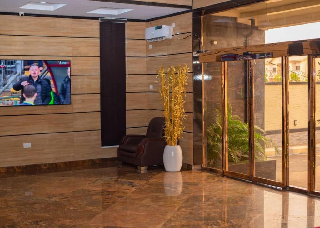 a lobby with a tv and a chair in a room at Gold Rhino Hotel and Suites Ltd in Enugu