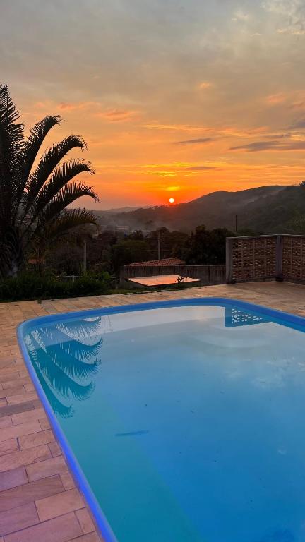 a blue swimming pool with a sunset in the background at Chácara Bella Vista Mairinque in Mairinque