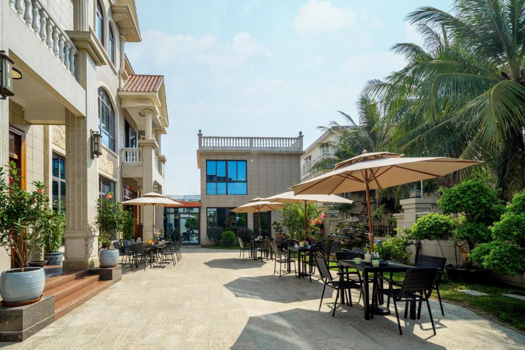 an outdoor patio with tables and chairs and umbrellas at Weisi Zhenpin Holiday Courtyard in Wushi