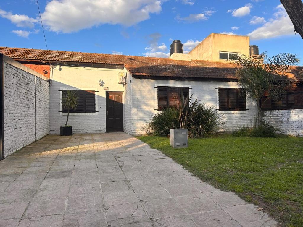 ein weißes Backsteinhaus mit einer Einfahrt davor in der Unterkunft Casa Barrio Los Sauces in Chascomús