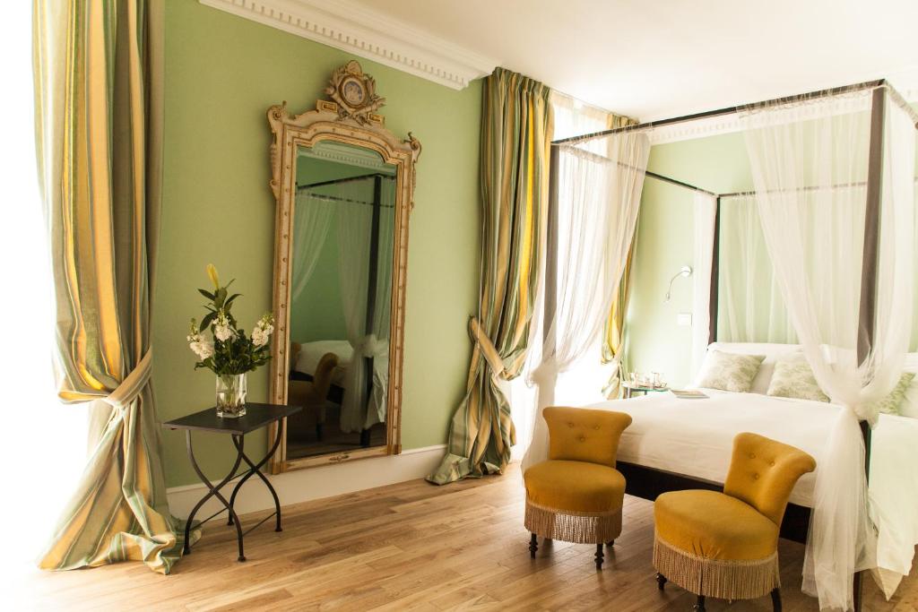 a bedroom with a bed and a mirror and two chairs at Palazzo del Senatore in Atina