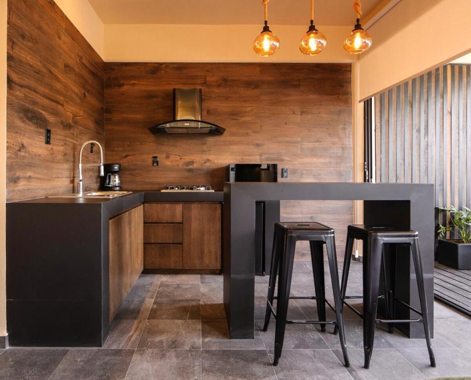 a kitchen with a black counter and stools at Bonito departamento en Avandaro in Valle de Bravo