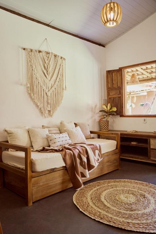a bedroom with a bed and a couch and a mirror at Vila Três - A apenas 2 minutos da praia! in Caraíva