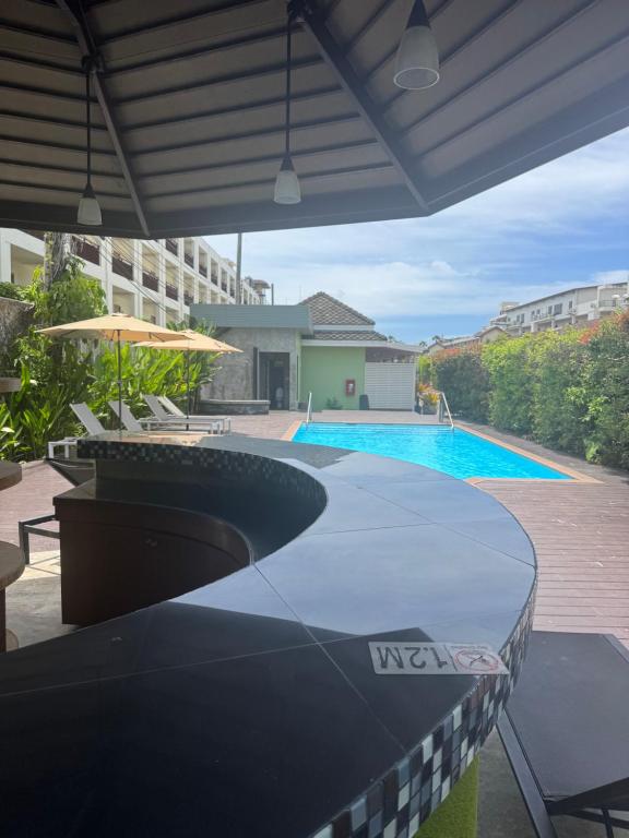uma vista para uma piscina com uma mesa e um guarda-sol em Spice & Sea Resort em Kata Beach