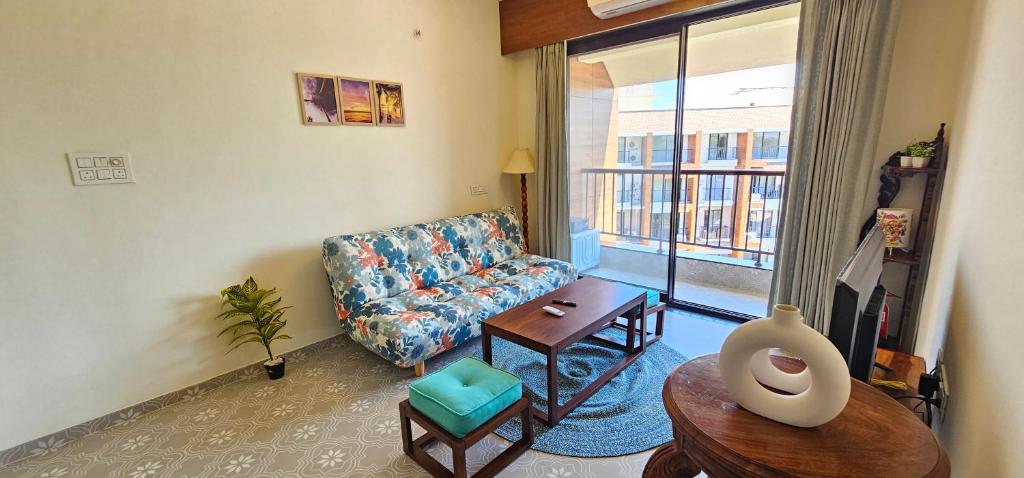 a living room with a couch and a table at Elegant 1BHK Couples Getaway with River View, Pool, Gym, Amenities - Near Candolim Beach in Candolim