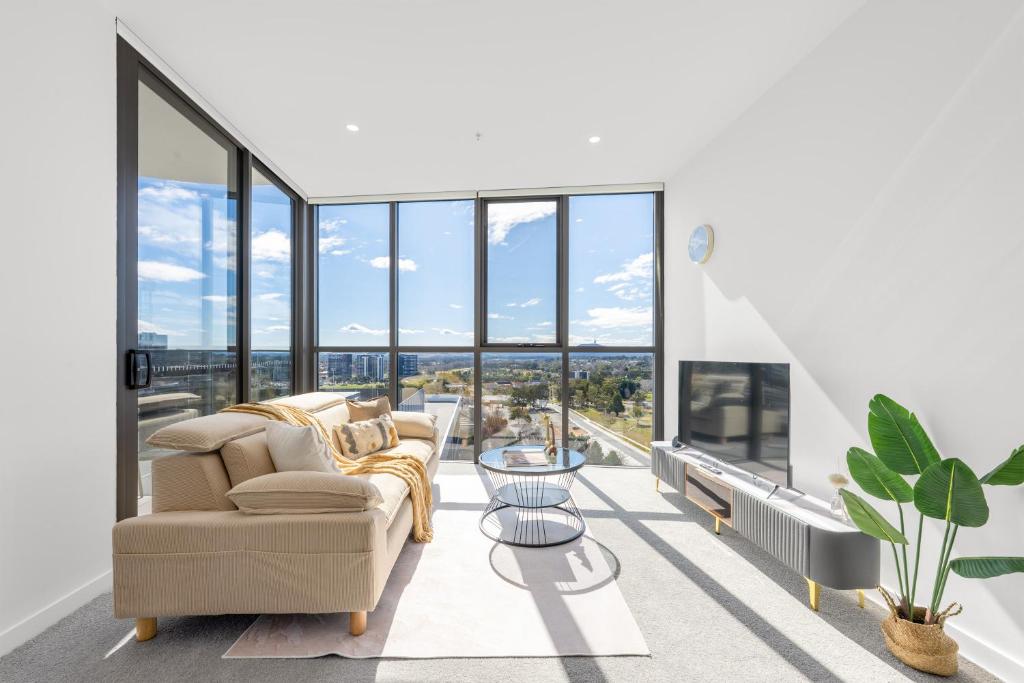 a living room with a couch and large windows at Sunny Central Woden Apt,Hospital, CIT , Pool in Phillip