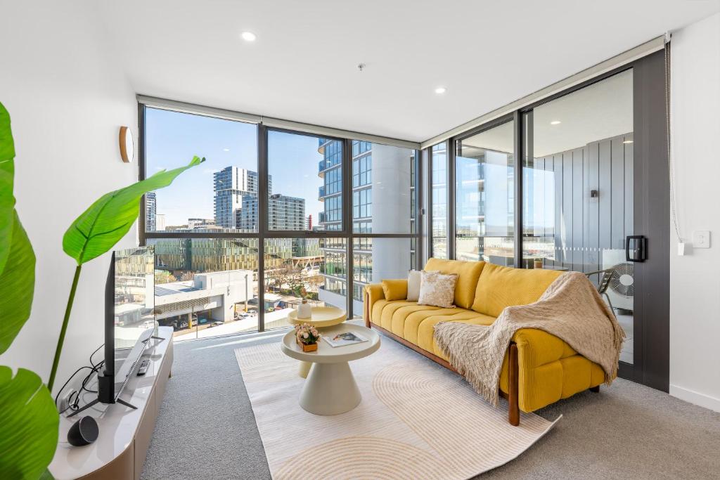 a living room with a yellow couch and large windows at Chic Woden Apt, Near Hospital, Westfield w Pool in Phillip