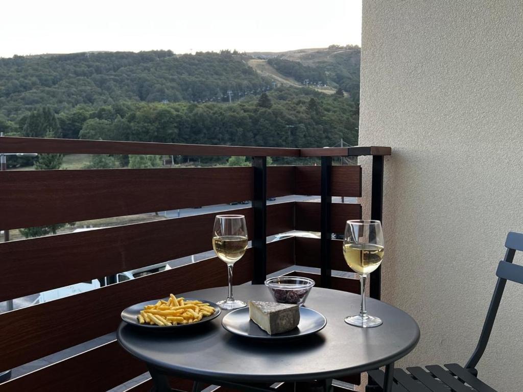 a table with two glasses of wine and cheese at Studio moderne à Super Besse, vue lac des Hermines - FR-1-814-136 in Super Besse