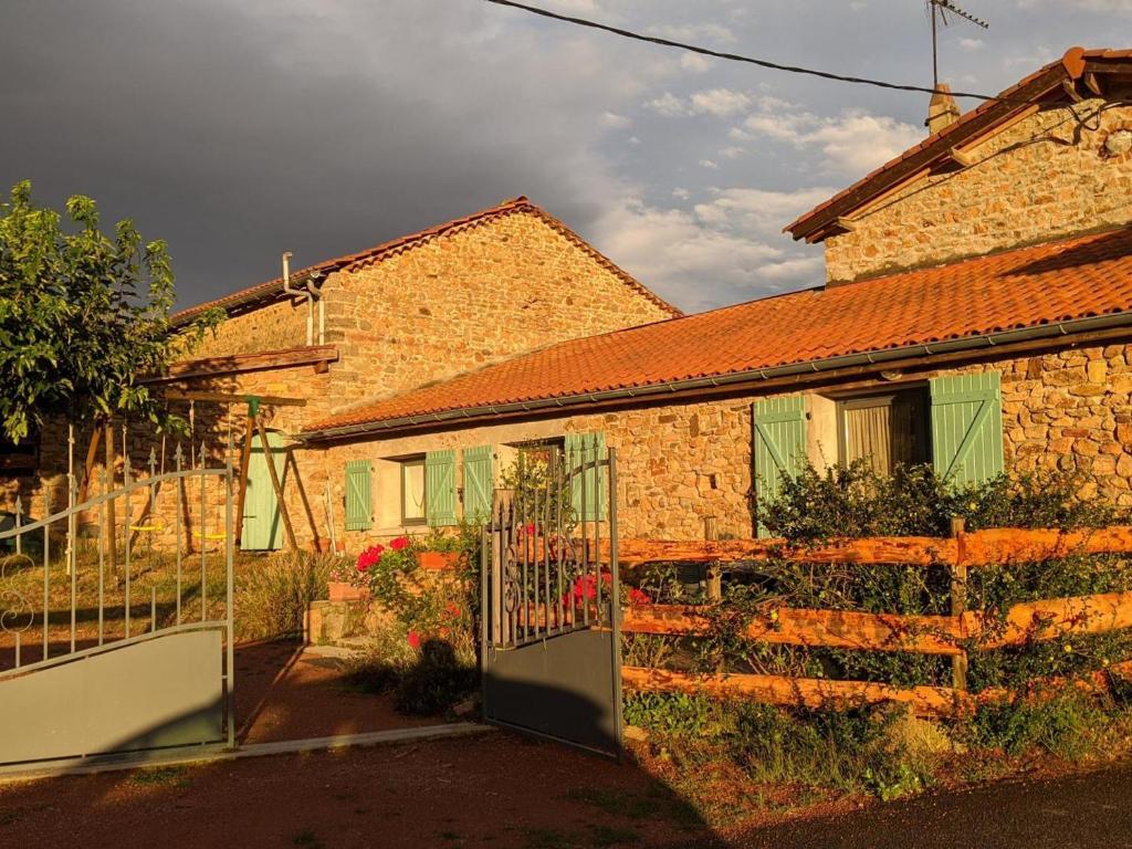 una casa di mattoni con un cancello di fronte di Gîte rural confortable avec terrasse, proche de Roanne - FR-1-496-376 a Vendranges