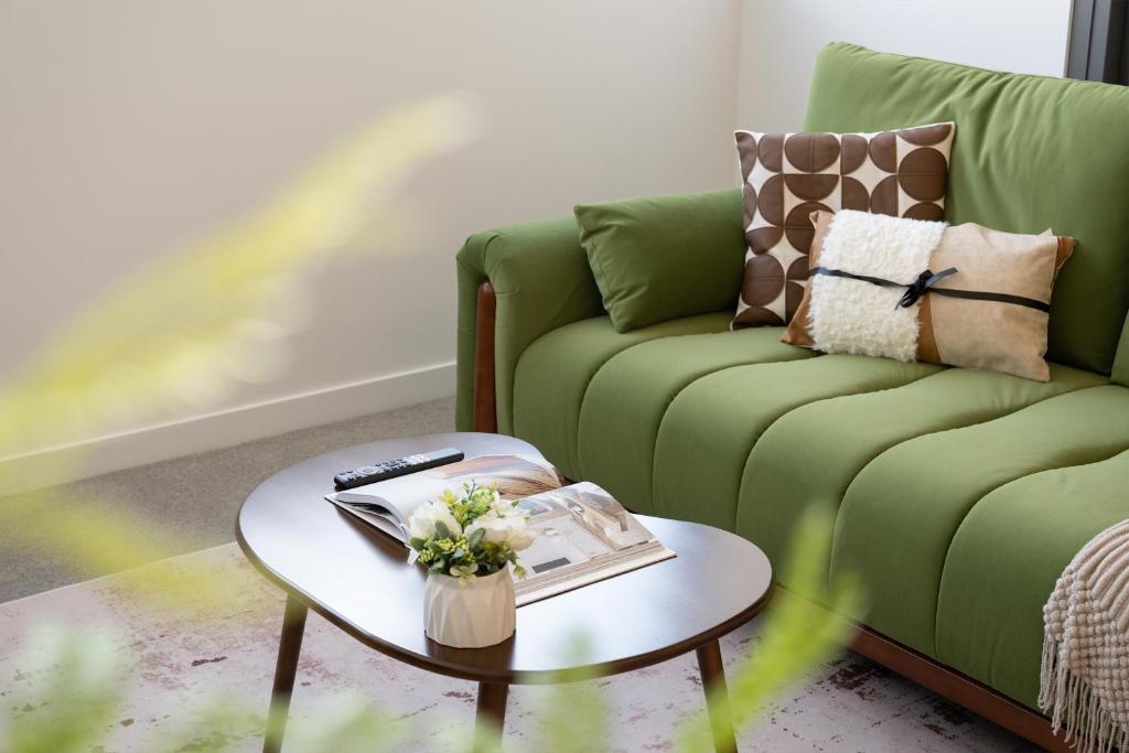 a living room with a green couch and a table at Cozy Woden Stay, Hospital, Mall, Pool, Parking in Phillip