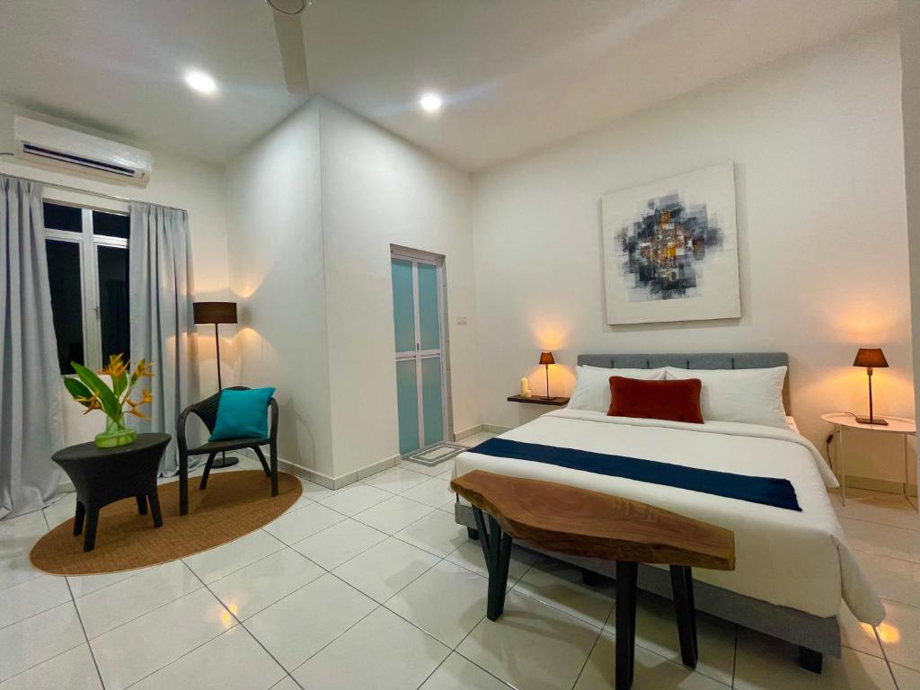 a bedroom with a large bed and a chair at Bloc Guesthouse in Pantai Cenang