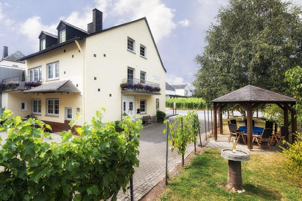 ein weißes Haus mit einem Pavillon und einigen Reben in der Unterkunft Gästehaus Scholtes-Hammes in Trittenheim