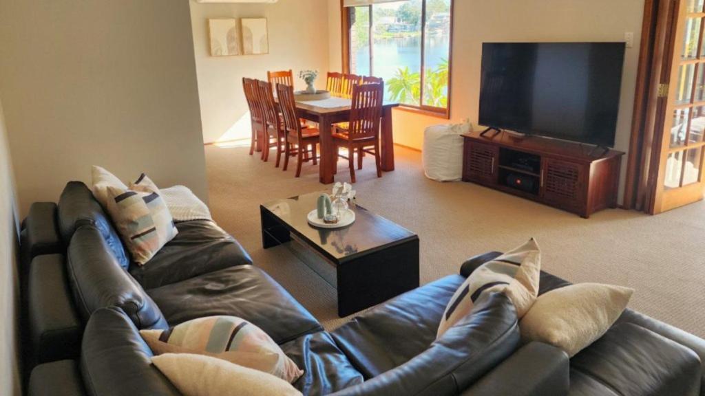 a living room with a leather couch and a television at A Slice Of Paradise in Sussex inlet