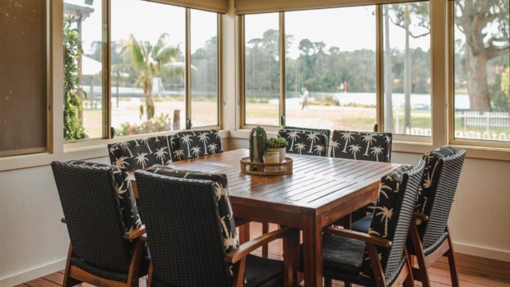 a dining room with a wooden table and chairs at Riverfront Retreat Sussex House Park in Sussex inlet