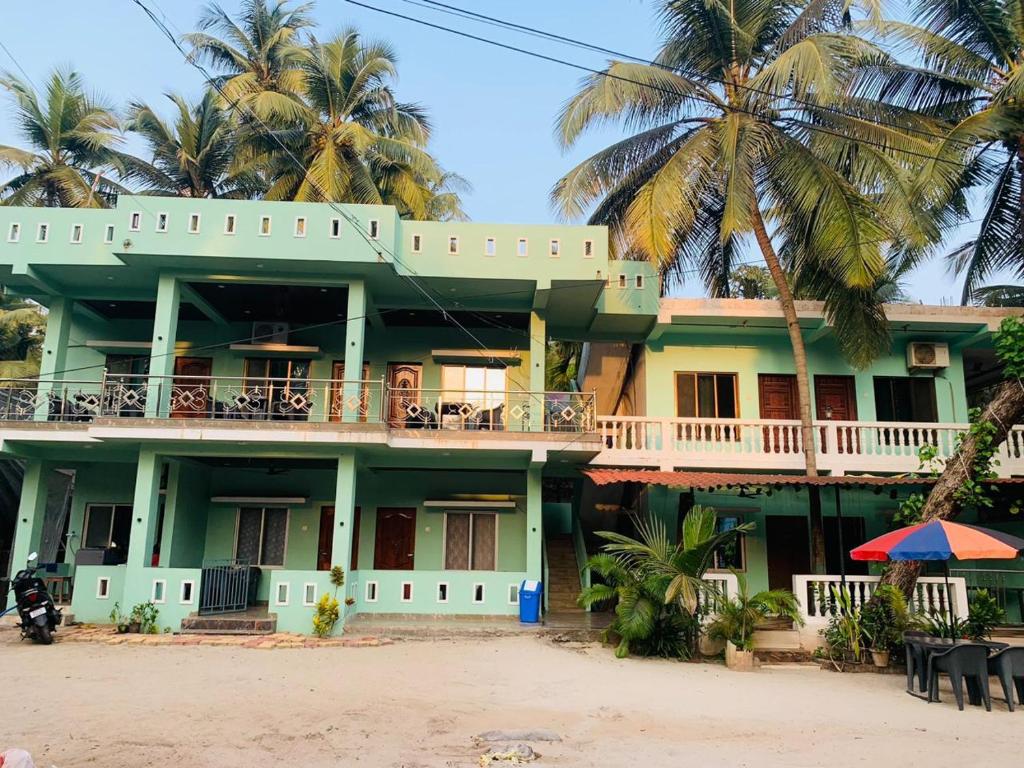 een gebouw op het strand met palmbomen bij Swayambhu Resort in Malvan