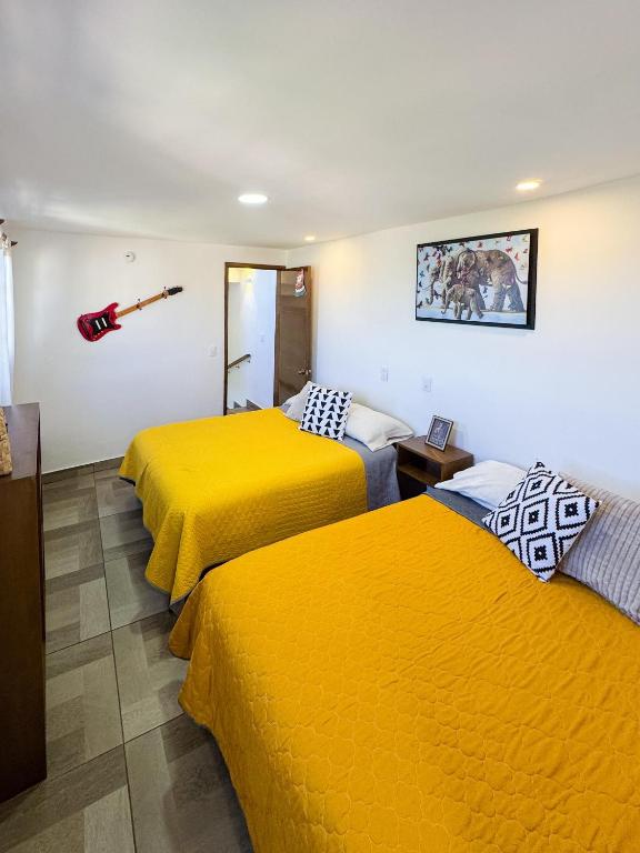 two beds in a room with yellow sheets at Casa Sac Nicte Tlalpujahua in Tlalpujahua de Rayón