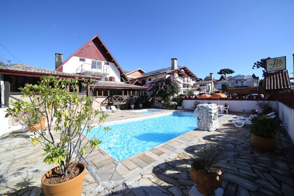 a swimming pool in a yard with plants in pots at Hotel JB in Campos do Jordão